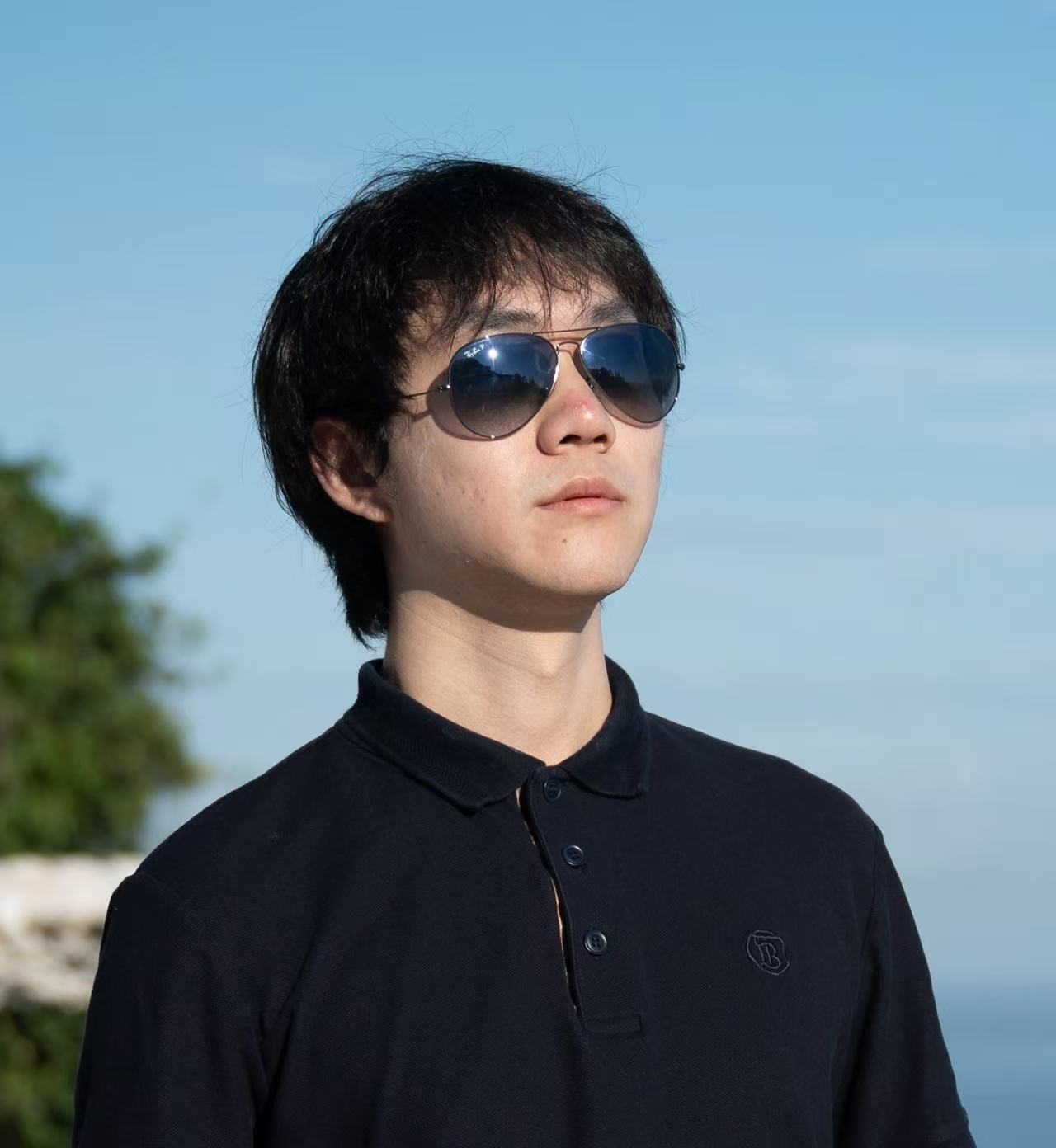 Chen Feng wearing sunglasses outdoors under a blue sky